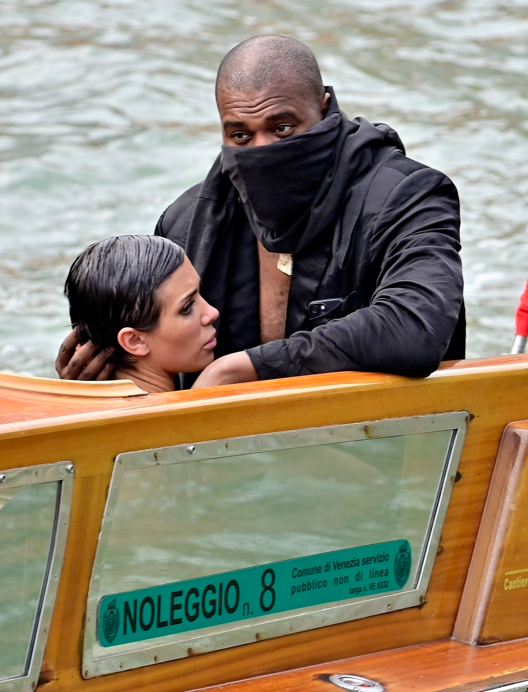 Kanye West with his face covered and Bianca Censori on a water taxi in Venice.