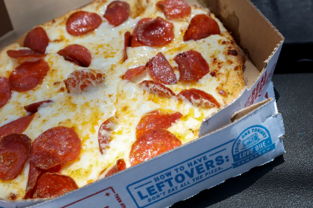 Photo illustration of a Domino's pepperoni pizza in a partially open pizza box.