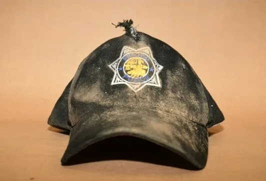 A dirty, tattered black baseball cap with a Fresno Police Department star-shaped emblem.