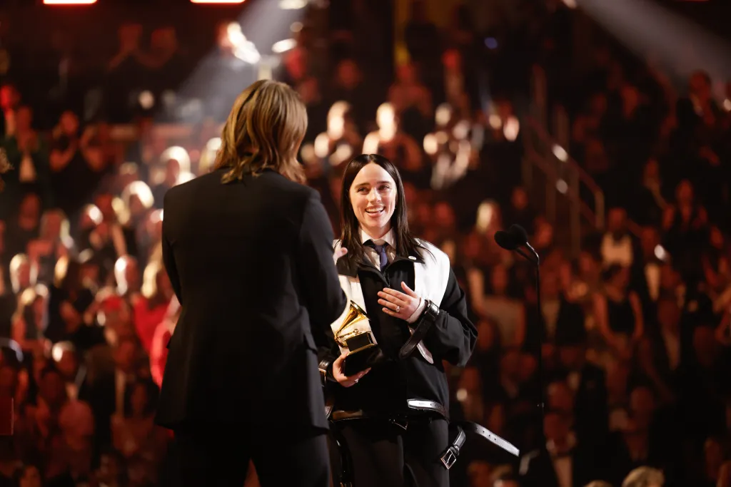 Billie Eilish holding a Grammy Award and smiling at the 68th Annual Grammy Awards.