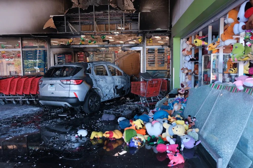 A charred vehicle and scattered stuffed animals lie outside a damaged supermarket in Guadalajara, Jalisco state, Mexico.