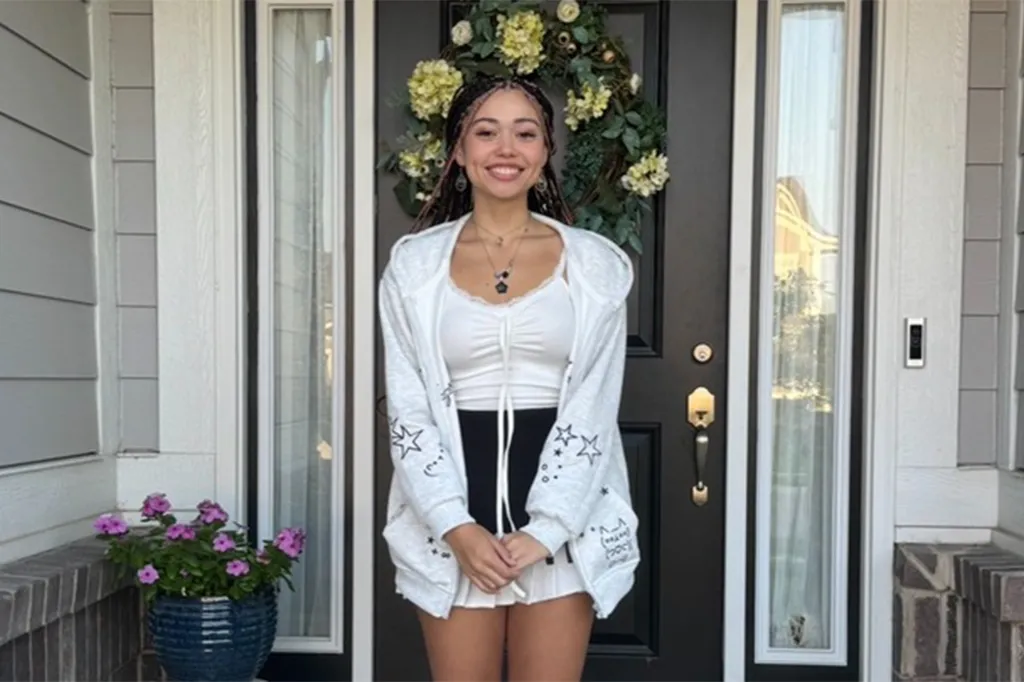Hailey Buzbee, a smiling teen with braids and a white hoodie, standing in front of a dark door with a wreath.