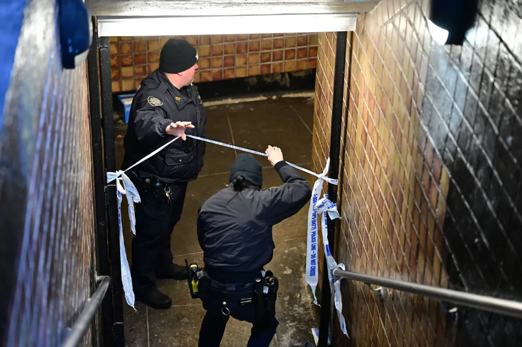 Two police officers taping off a subway staircase with 