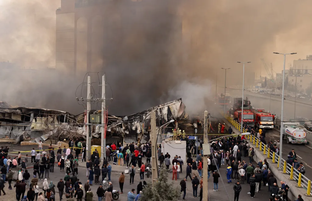 People watch as firefighters battle a fire at Jannat Bazaar in Tehran, Iran.