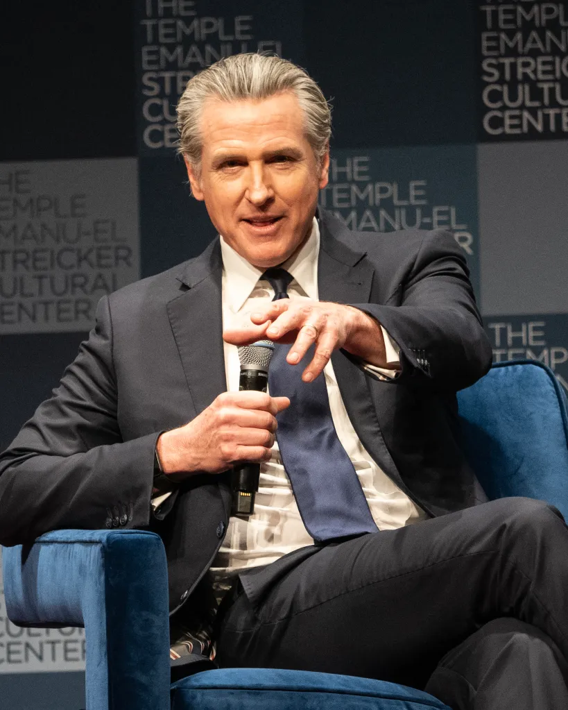 California Governor Gavin Newsom speaking and gesturing with a microphone during his 