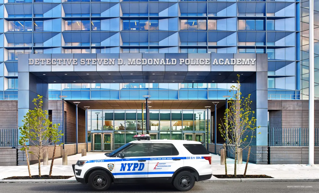 Illustration of the Detective Steven D. McDonald Police Academy with an NYPD vehicle parked outside.