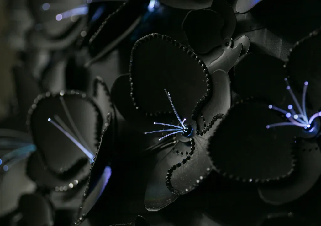 Close-up of a robotic dress with glowing optic fiber pieces resembling flower stamens.