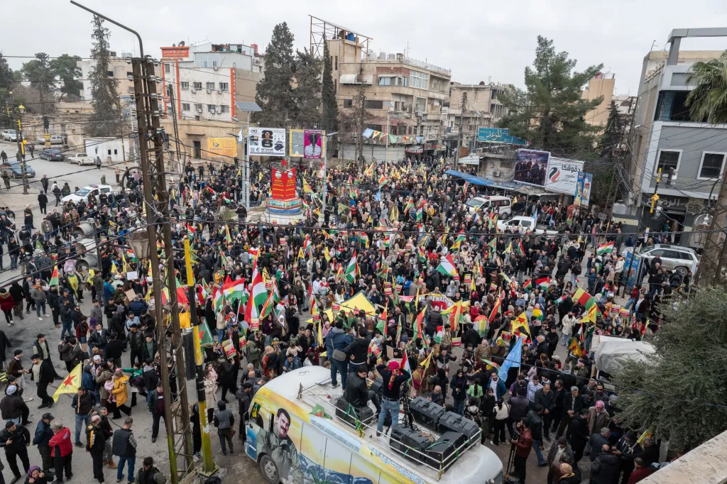 A large crowd of Kurdish protestors in Qamishli, Syria, carrying flags and signs during a march for human rights.