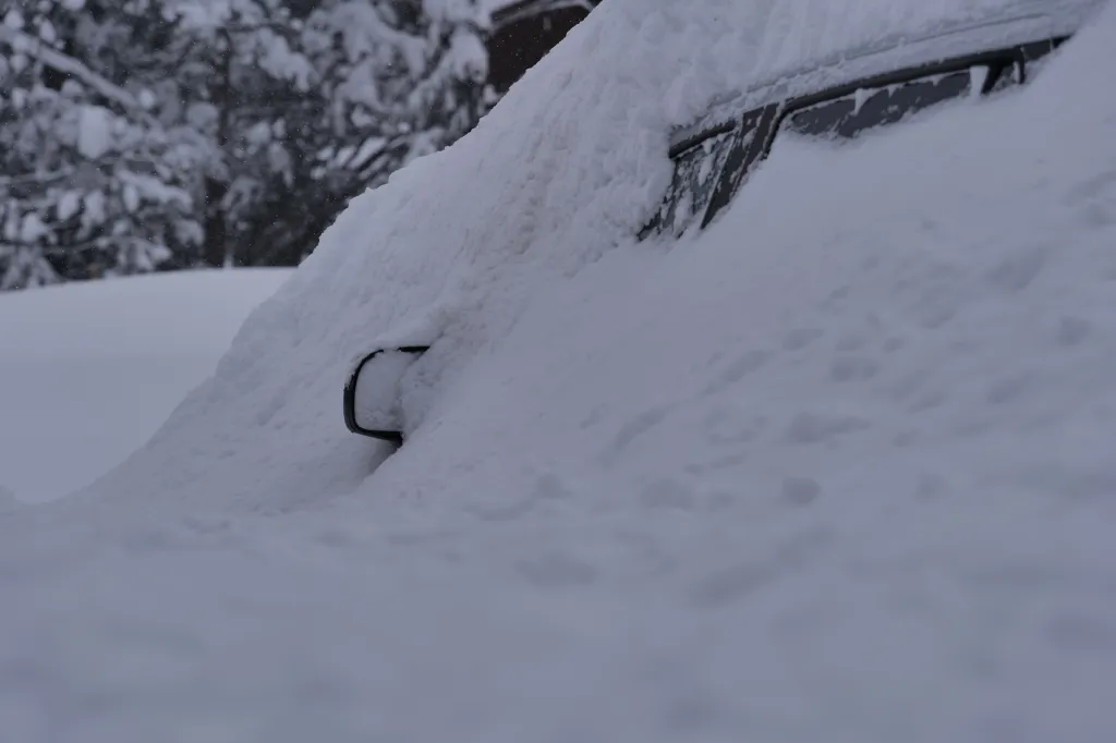 A car covered in deep snow in a Tahoe avalanche area.