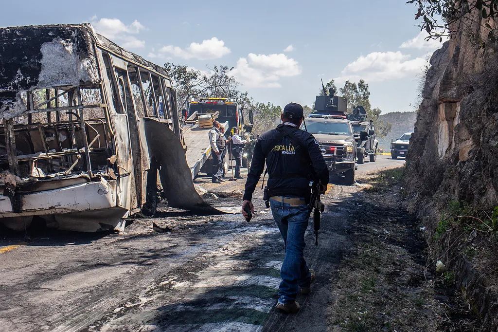 A convoy of the Mexican Army passes vehicles allegedly set on fire by members of organized crime.