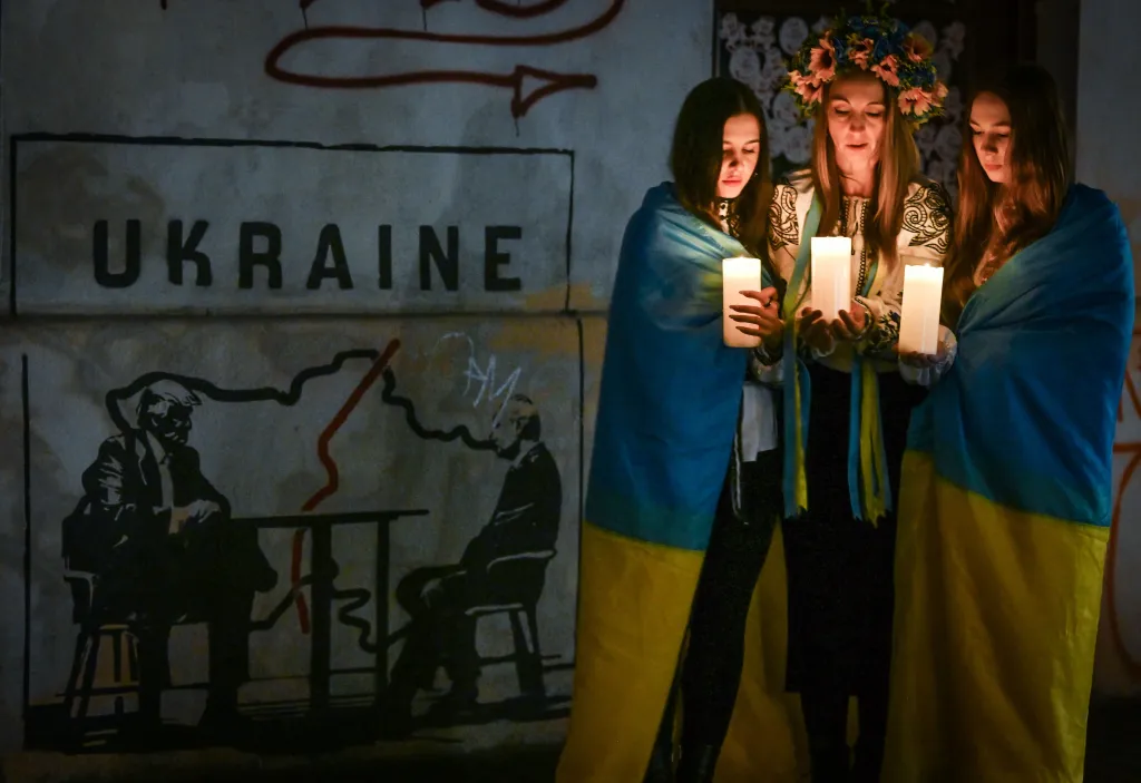 Three Ukrainian women holding candles participate in a candlelight vigil on Feb. 23, 2026. 