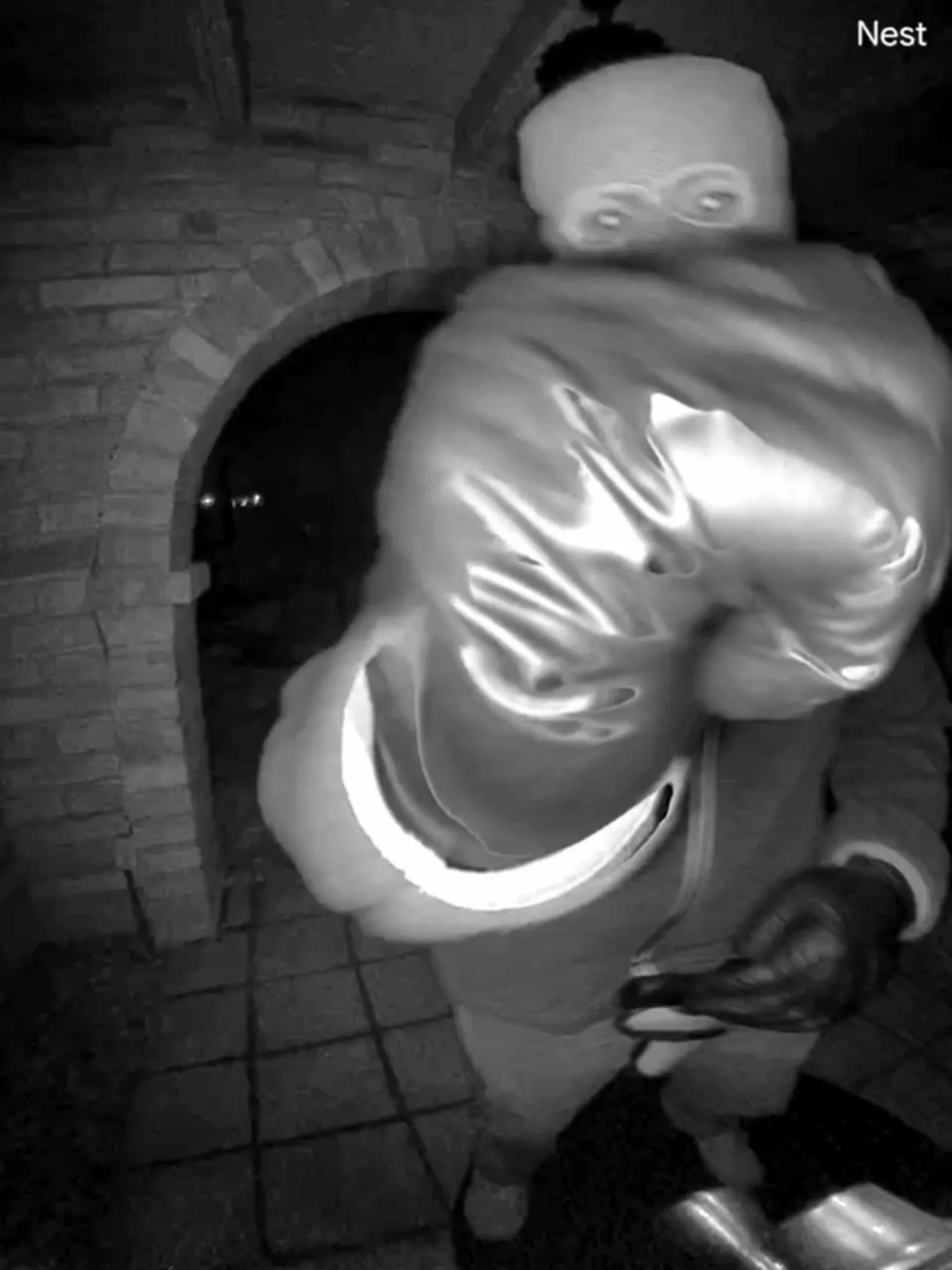 Surveillance footage of a person in a Santa costume and a ski mask with a large sack over their shoulder.
