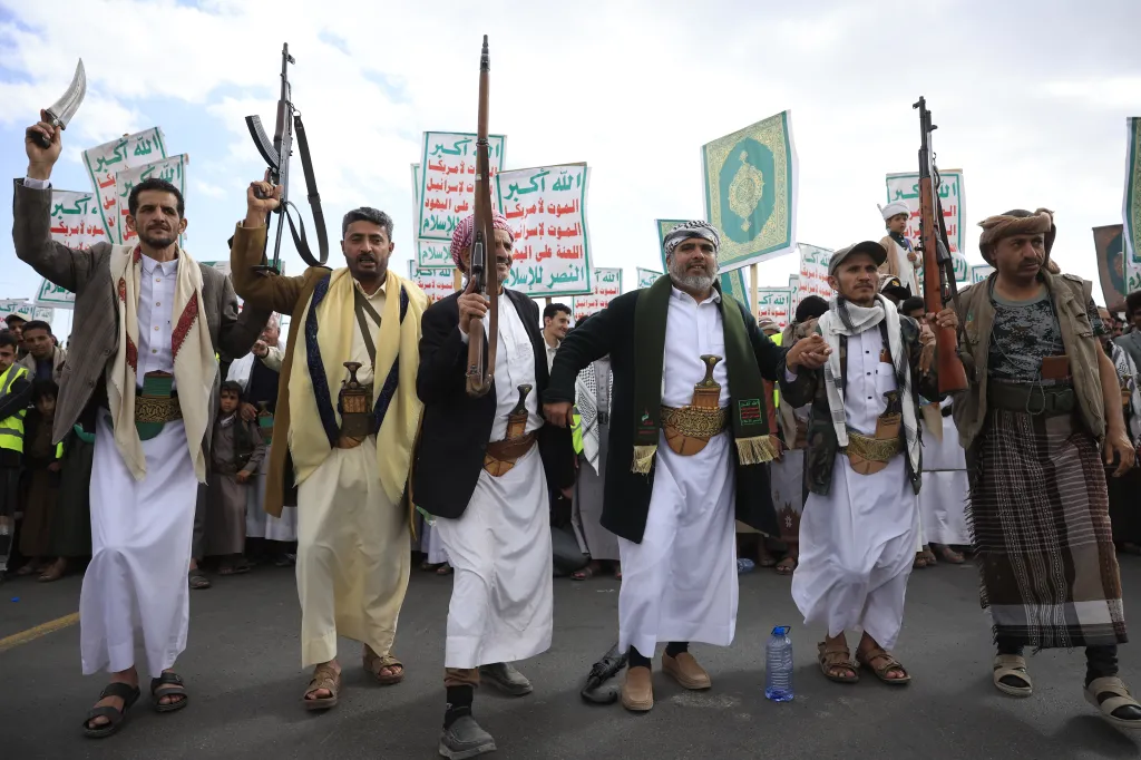Houthi supporters in Sanaa protest against the US and Israel, some carrying weapons and signs with anti-US and anti-Israel slogans.