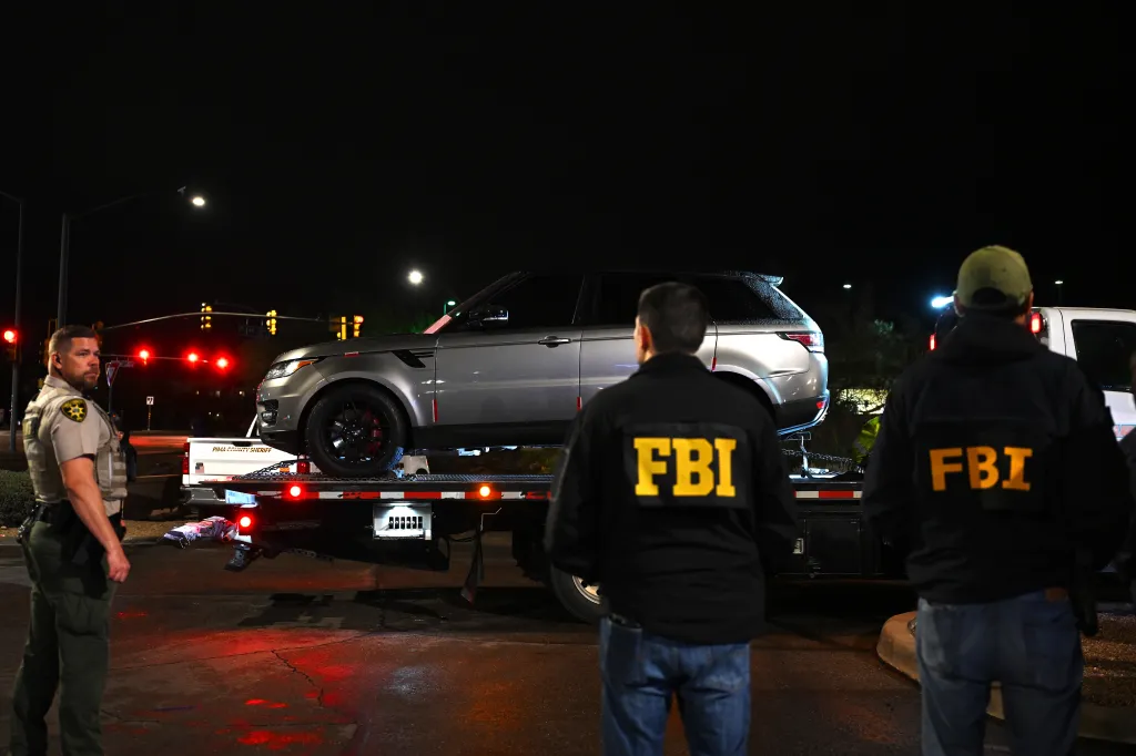 FBI agents watch as a gray Range Rover SUV is towed away from a parking lot outside a restaurant in Tucson, Arizona, on Feb. 13, 2026.