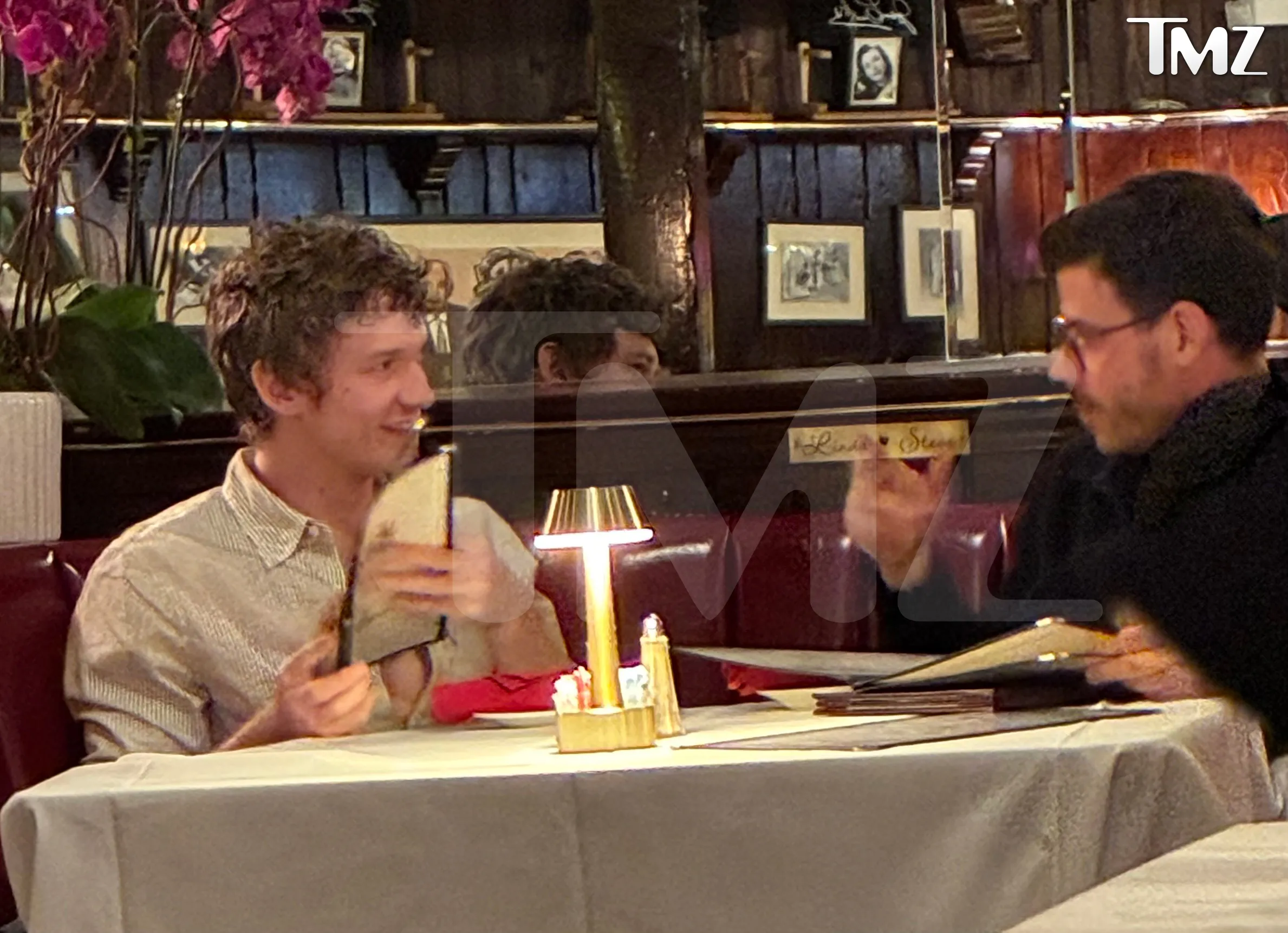 Connor Storrie and Francois Arnaud reviewing menus in a dimly lit restaurant.