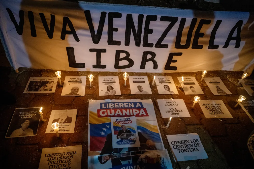 Candles and posters of political prisoners from Venezuela are laid on the ground during a vigil.