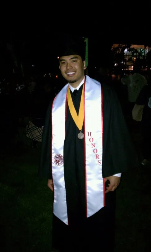 Man wearing a black graduation gown with an honors stole and medal.
