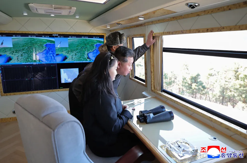 Kim Jong Un and his daughter observing a missile launch on monitors and through a window in a luxurious train.