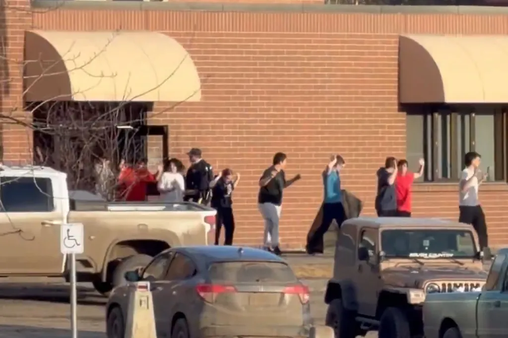 People with hands raised in front of a brick building.