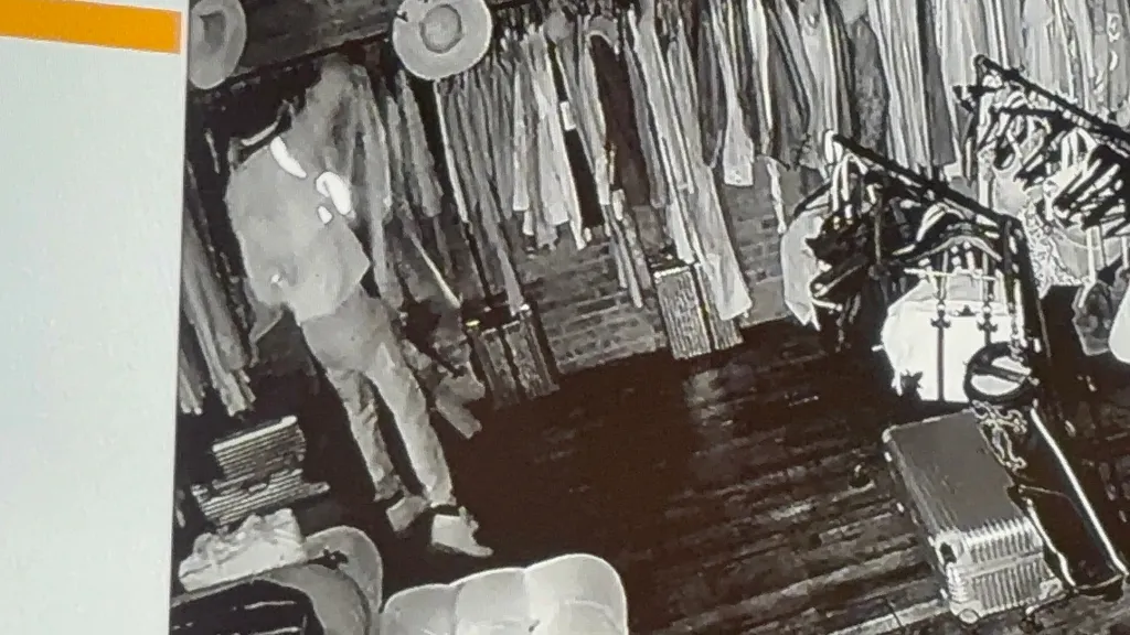 Surveillance image shows a suspect inside the 4G boutique, next to racks of clothing, during a robbery.