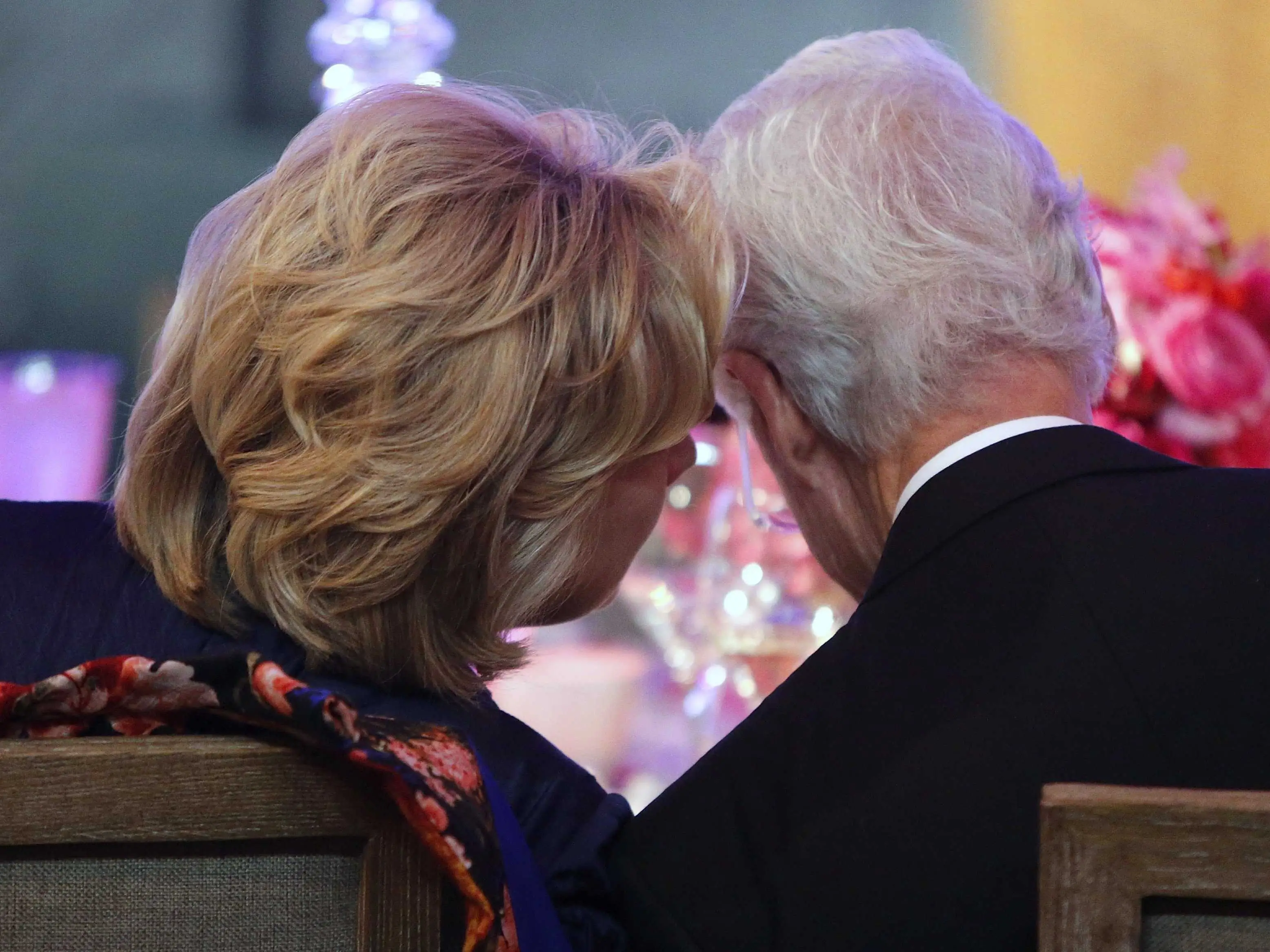 Hillary Clinton and Bill Clinton speak with their heads close to each other.