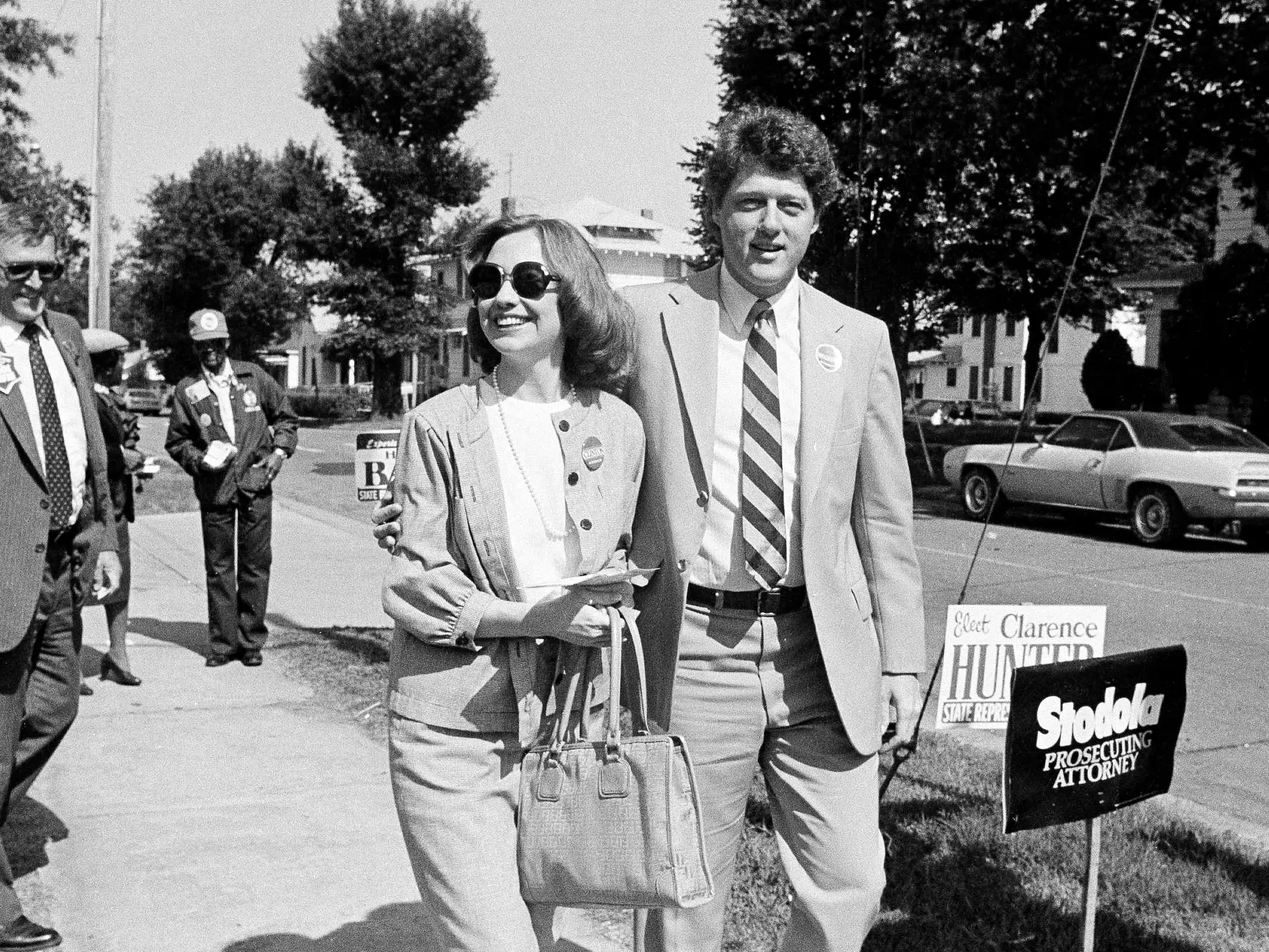 Hillary Clinton and Bill Clinton walk down a street.