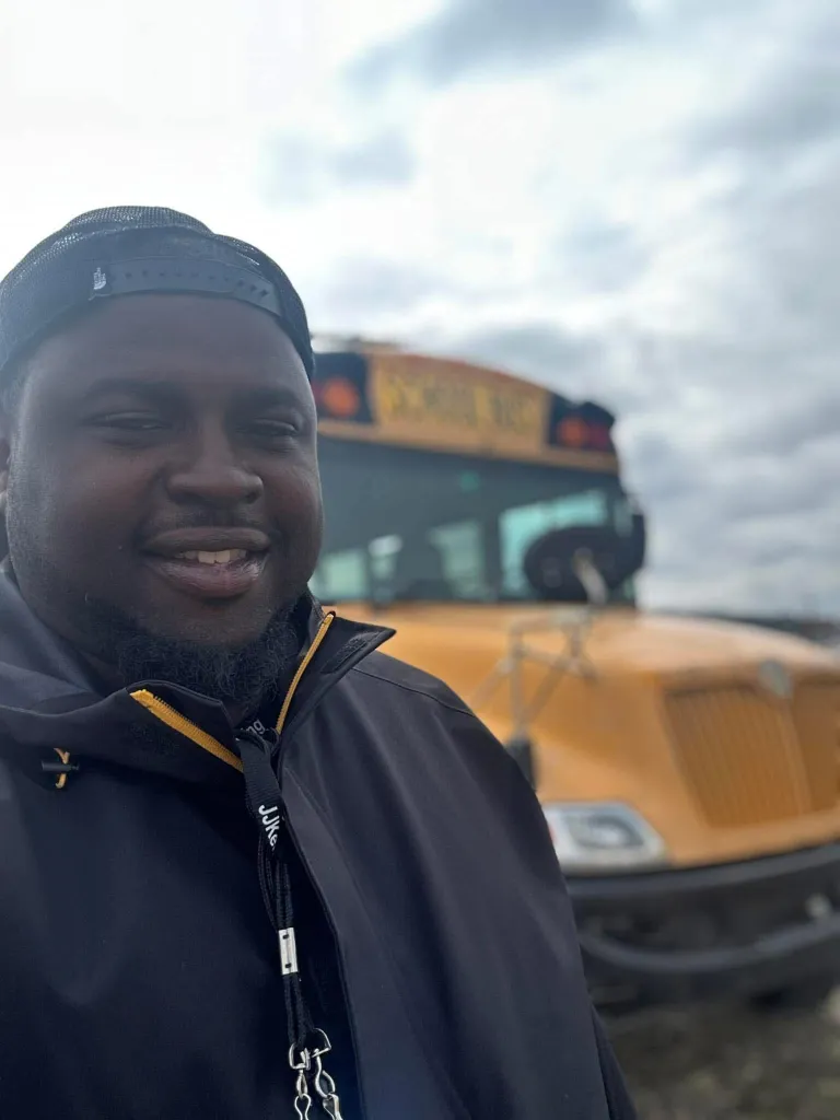 Darrell Beaver poses in front of his yellow school bus he uses as a contracted bus driver.