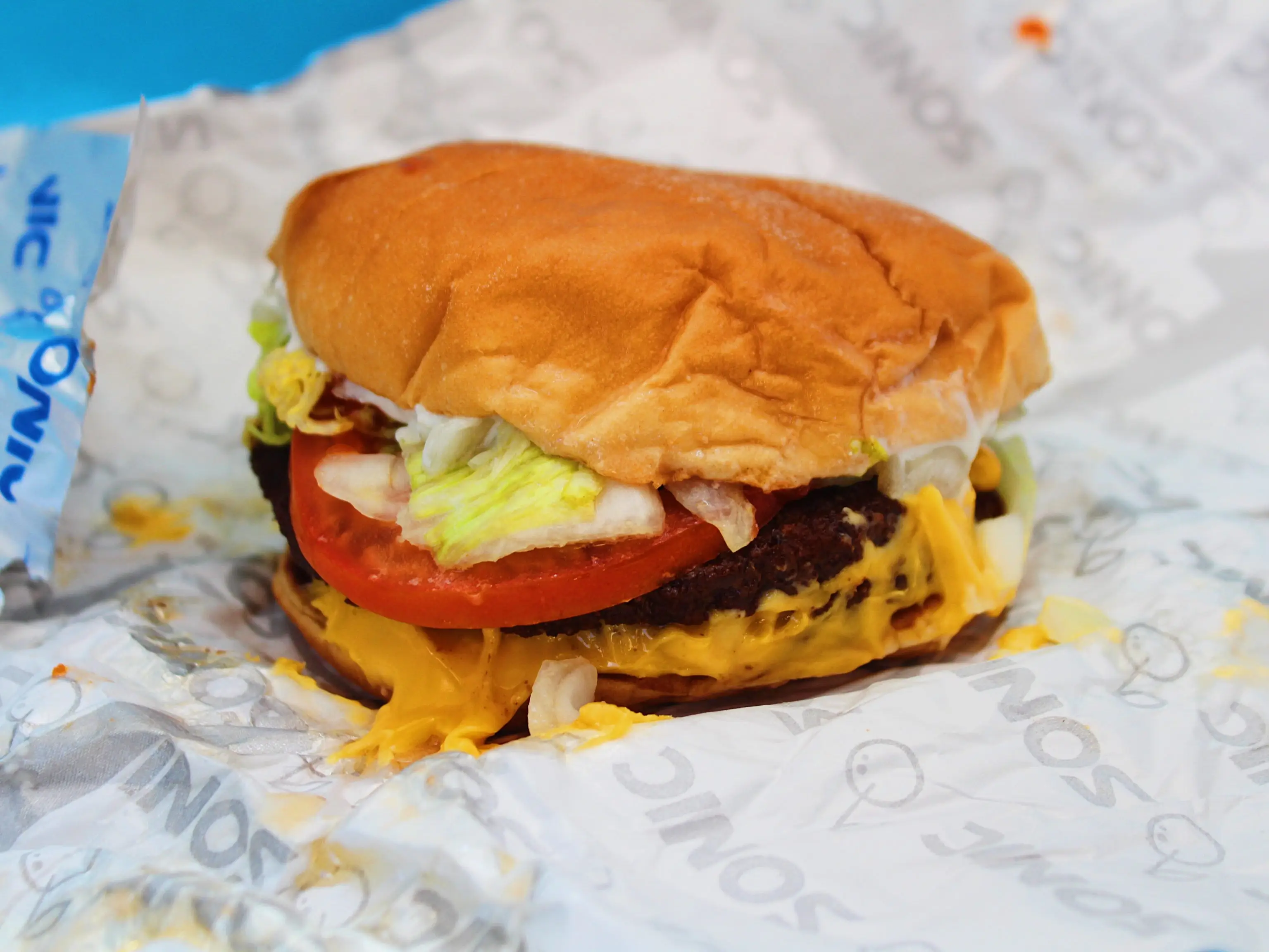 sonic double cheeseburger in tin foil wrapping on blue background