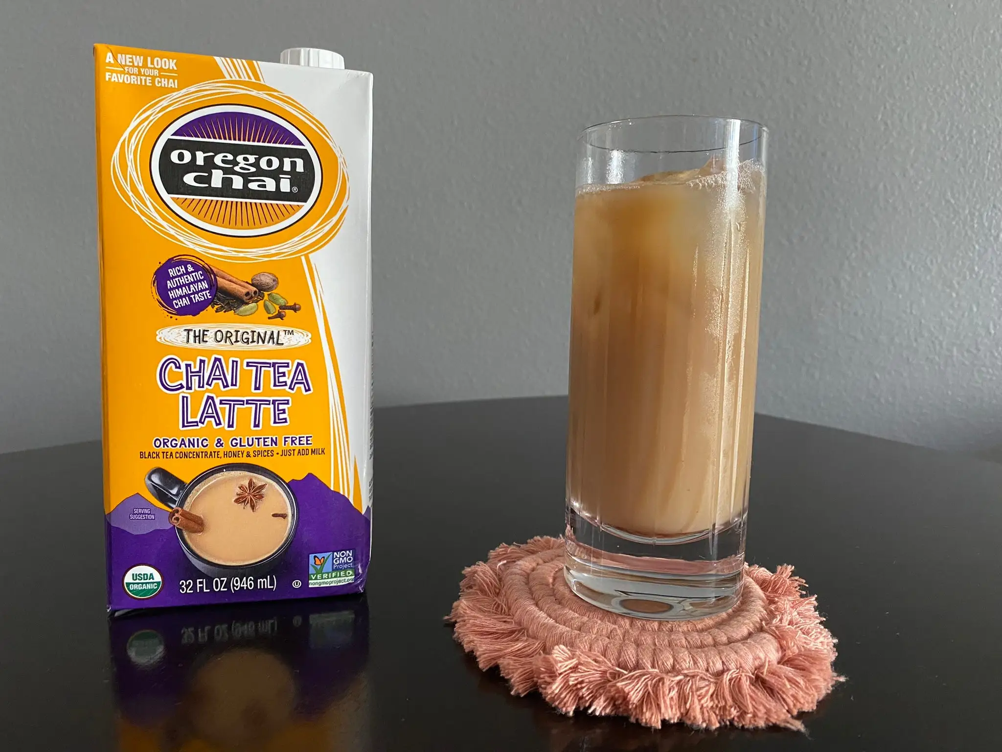Carton of Oregon Chai concentrate next to tall glass of iced chai latte.