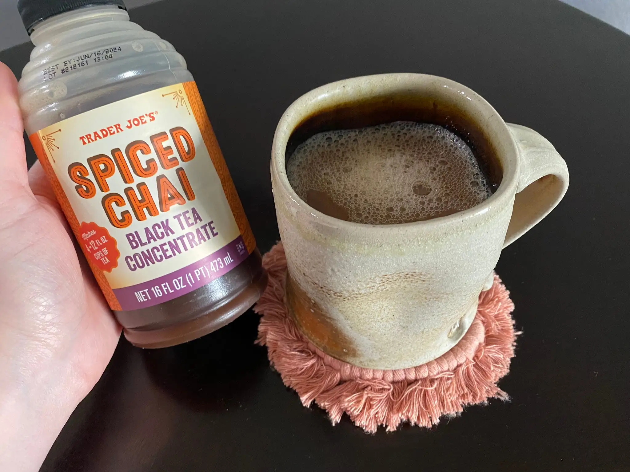 Author holding container of Trader Joe's chai concentrate next to mug of hot chai latte.