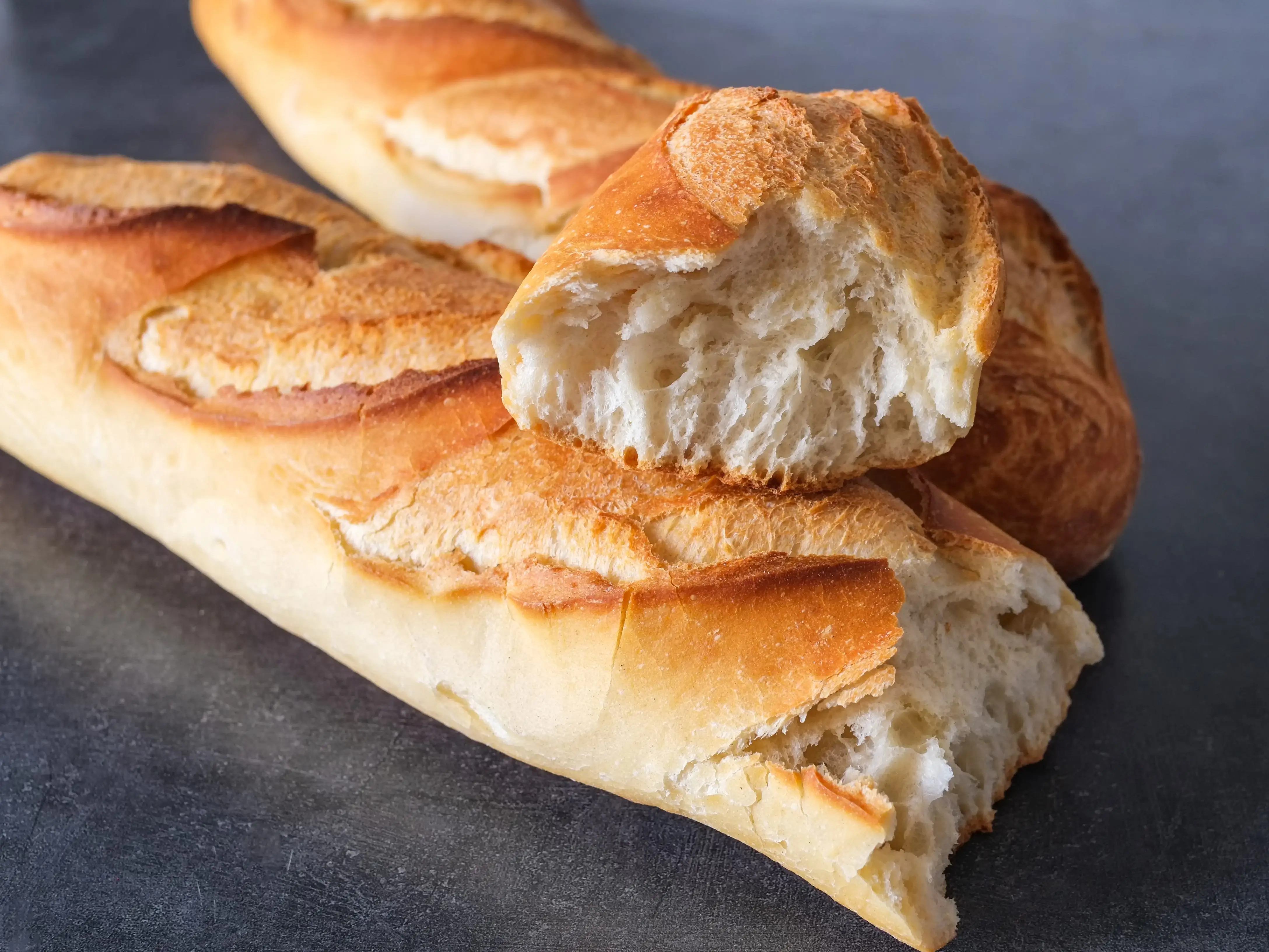 A closeup shot of baguette torn into three pieces.