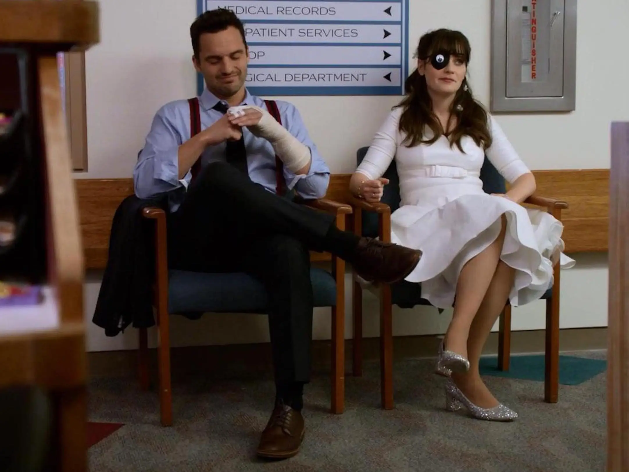 Nick and Jess sit in chairs at a hospital on 