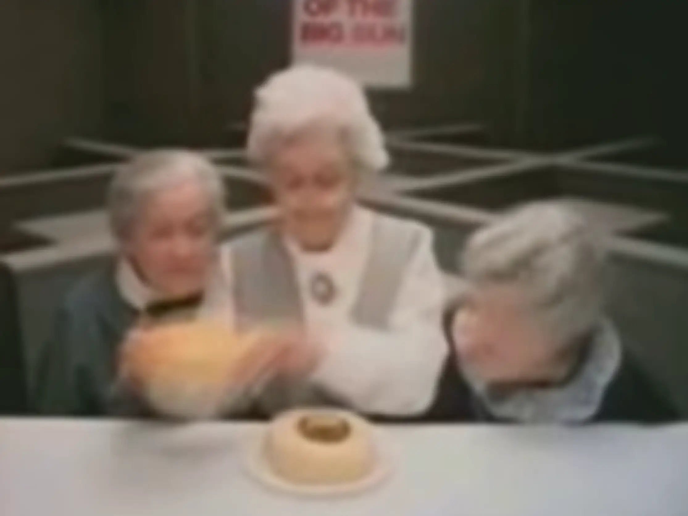 Three people inspect a burger with a very small patty.
