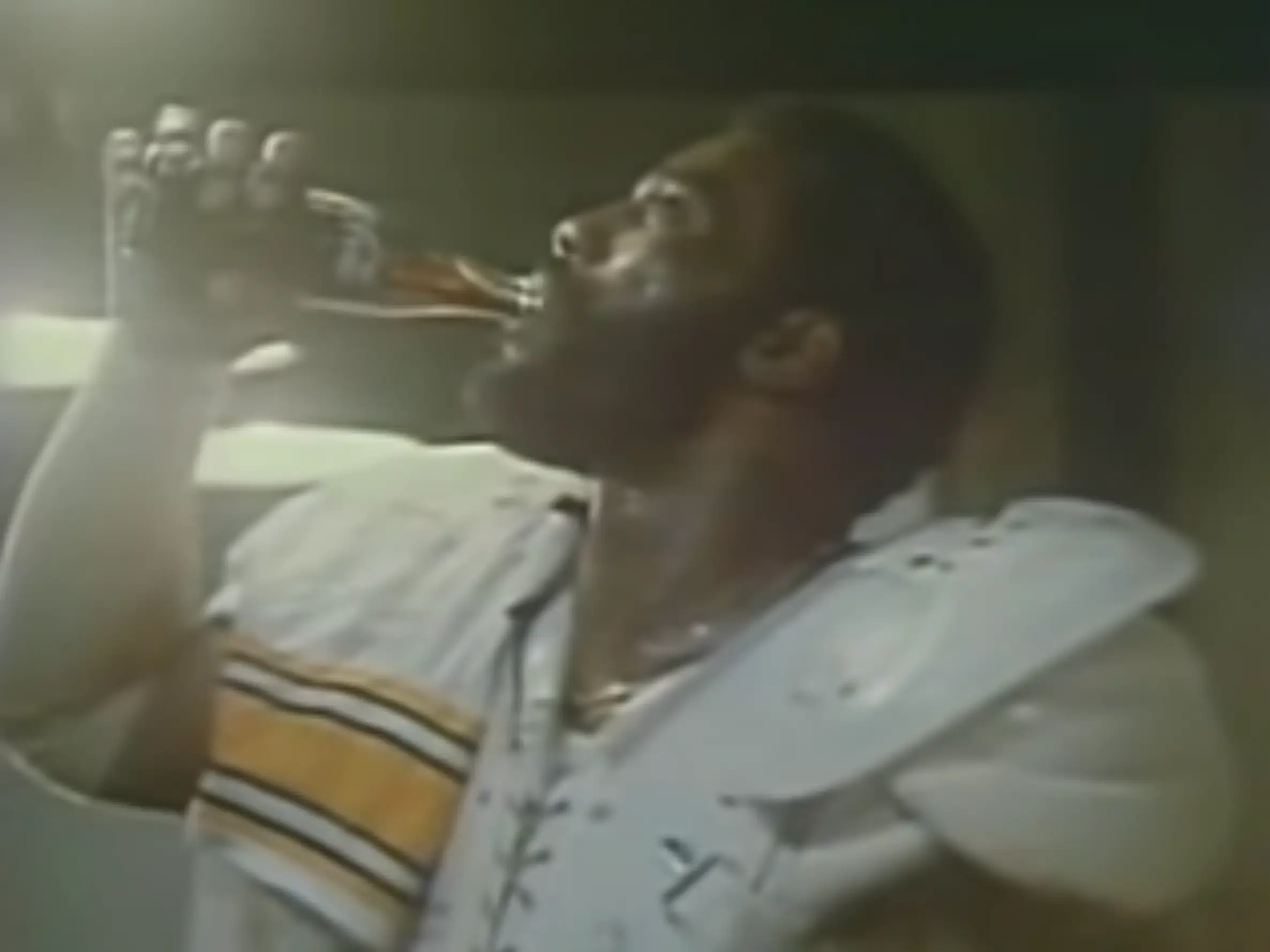 Joe Greene drinks a bottle of Coca-Cola.