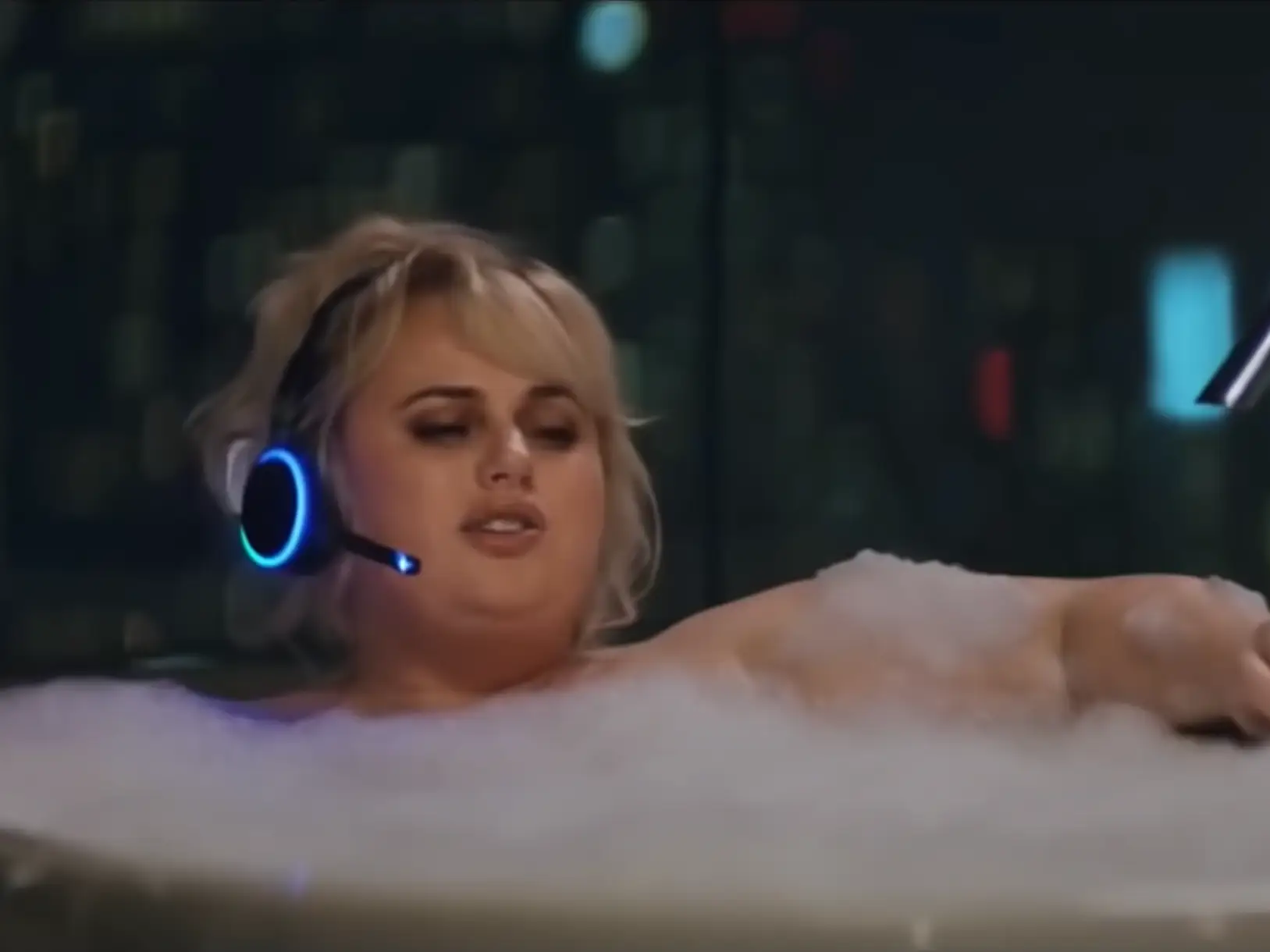 Rebel Wilson in a bubble bath with a headset on.