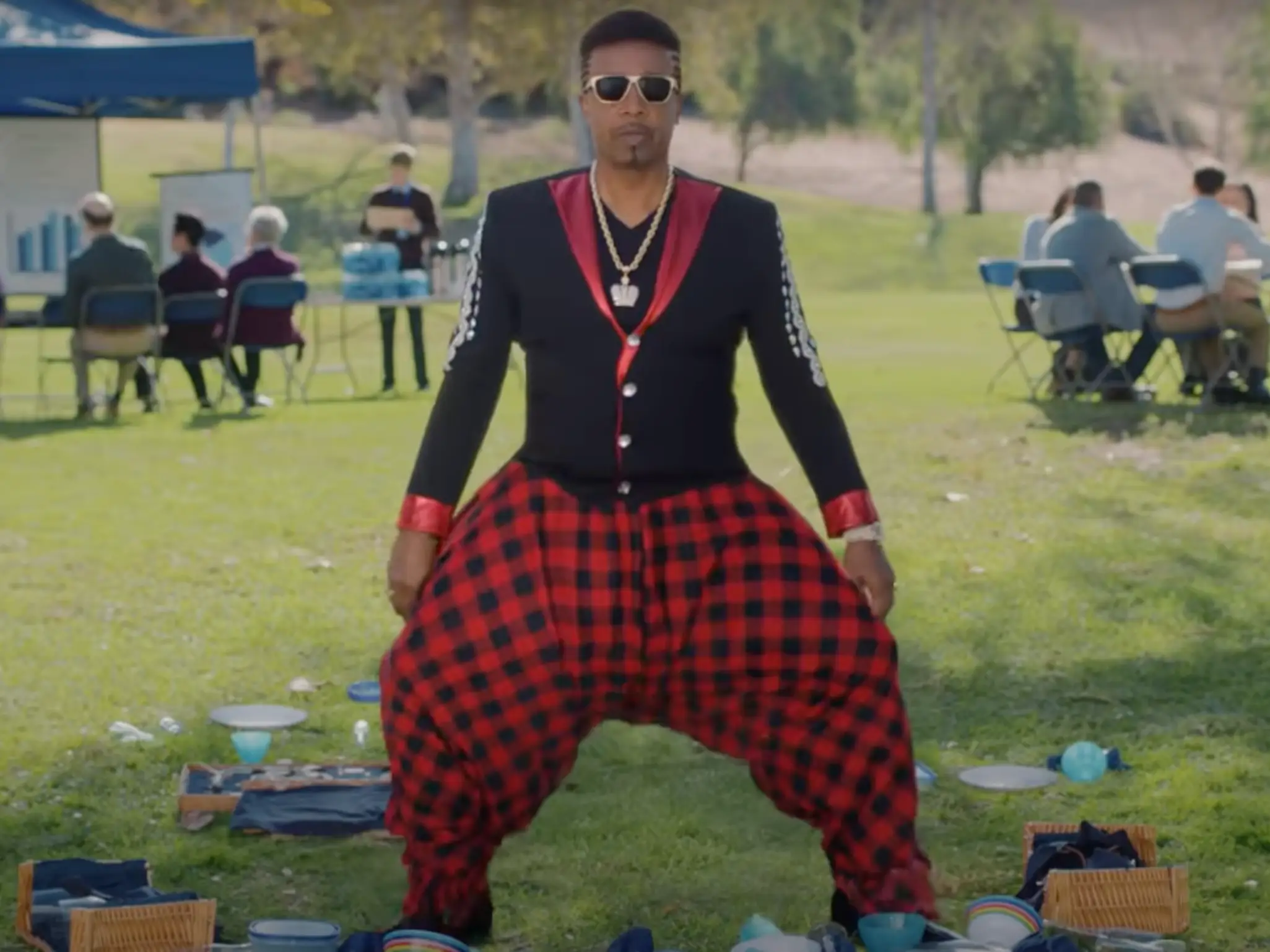 MC Hammer is in a park with his his signature parachute pants.