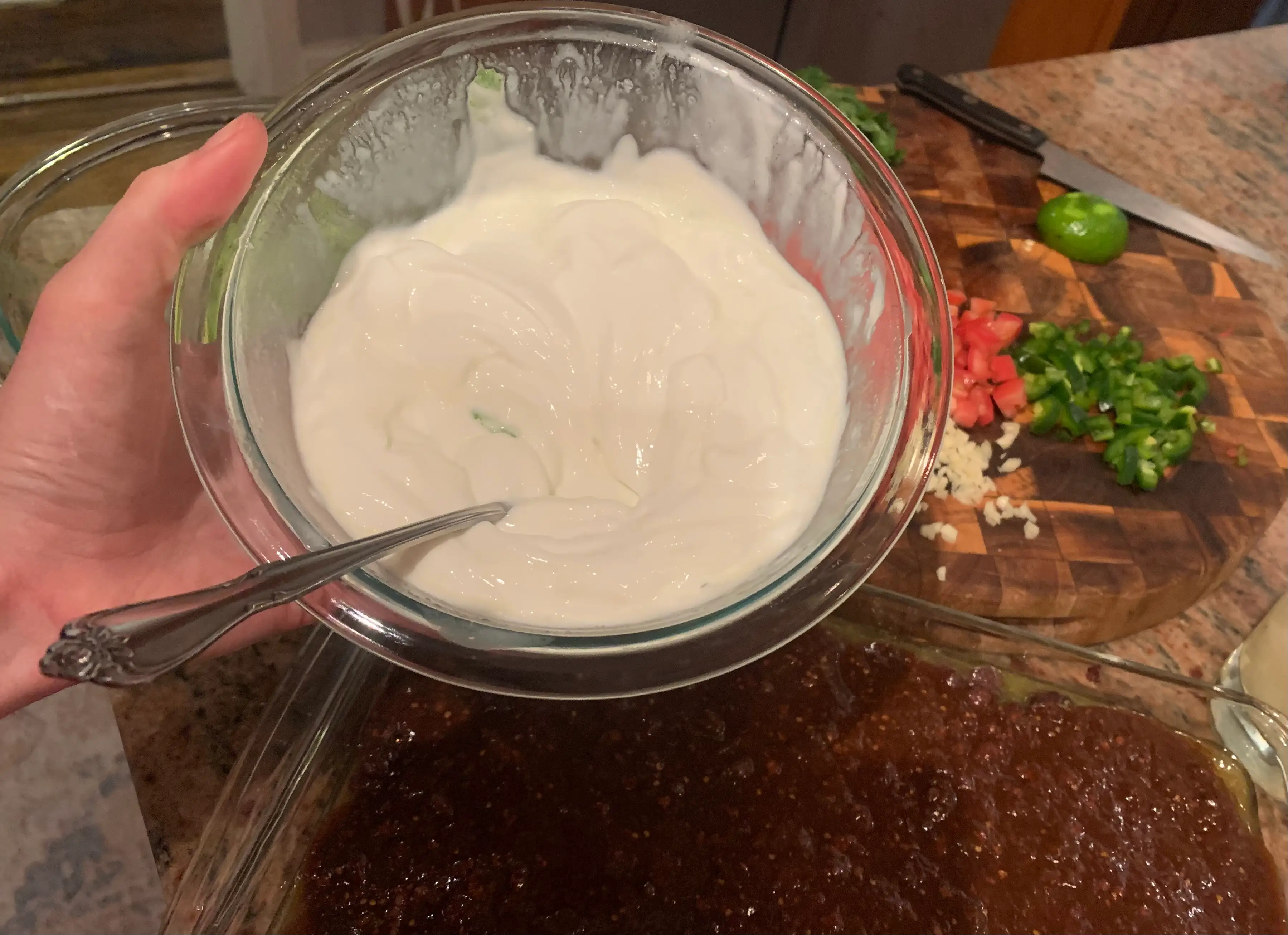 The writer holds a bowl of sour cream with visible pieces of lime zest mixed in