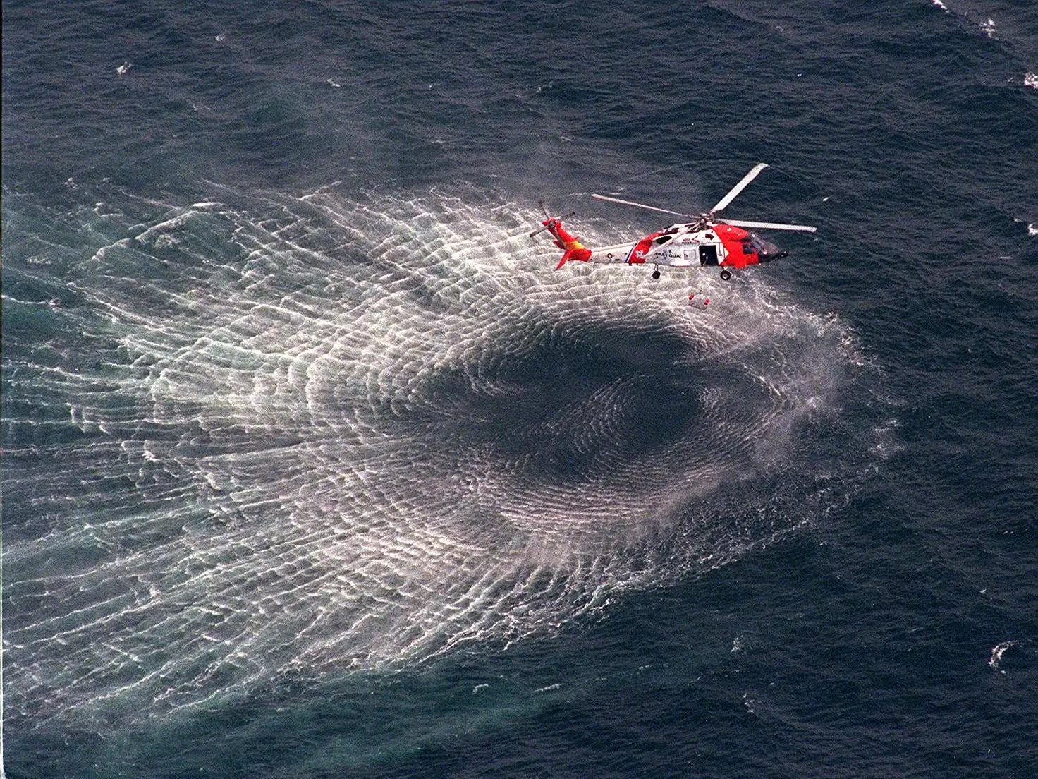 A Coast Guard helicopter lifts a rescue swimmer after the swimmer jumped into the water on July 17, 1999, to look for debris from John Kennedy Jr.'s plane