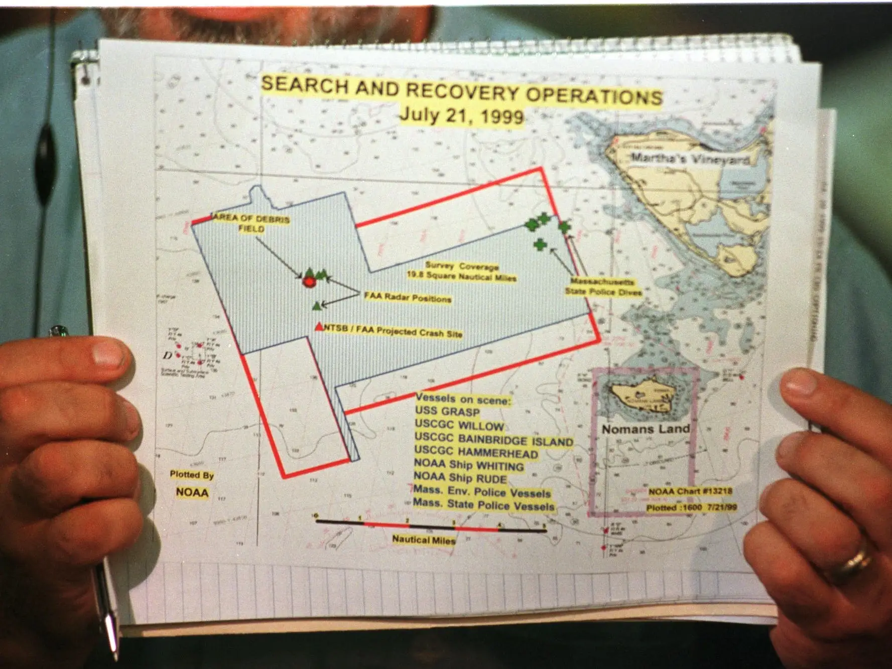 A television technician holds up the official handout map of the search and rescue area off Martha's Vineyard