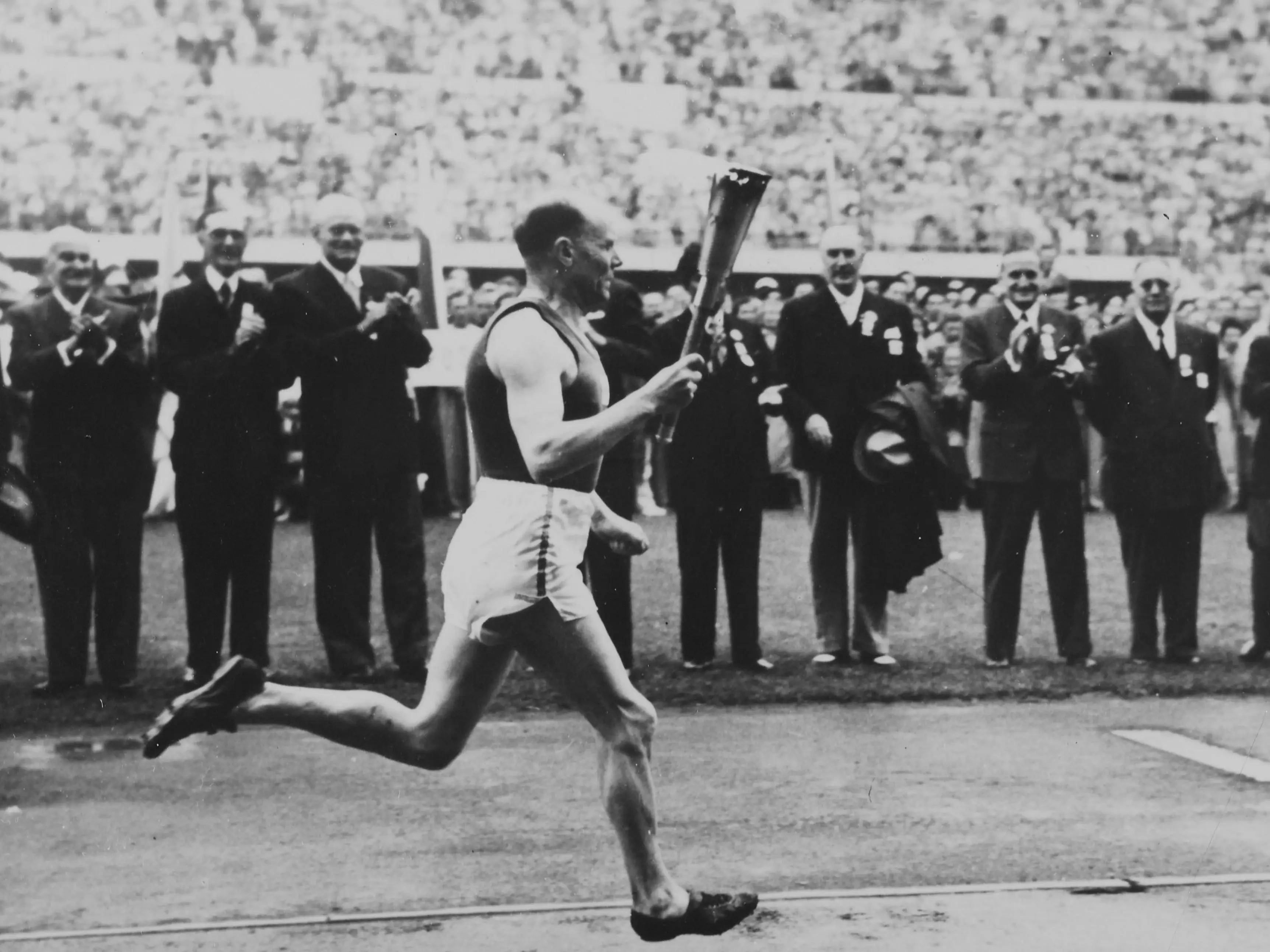 Paavo Nurmi ran with the Olympic torch at the 1952 Olympics in Helsinki as spectators watched.