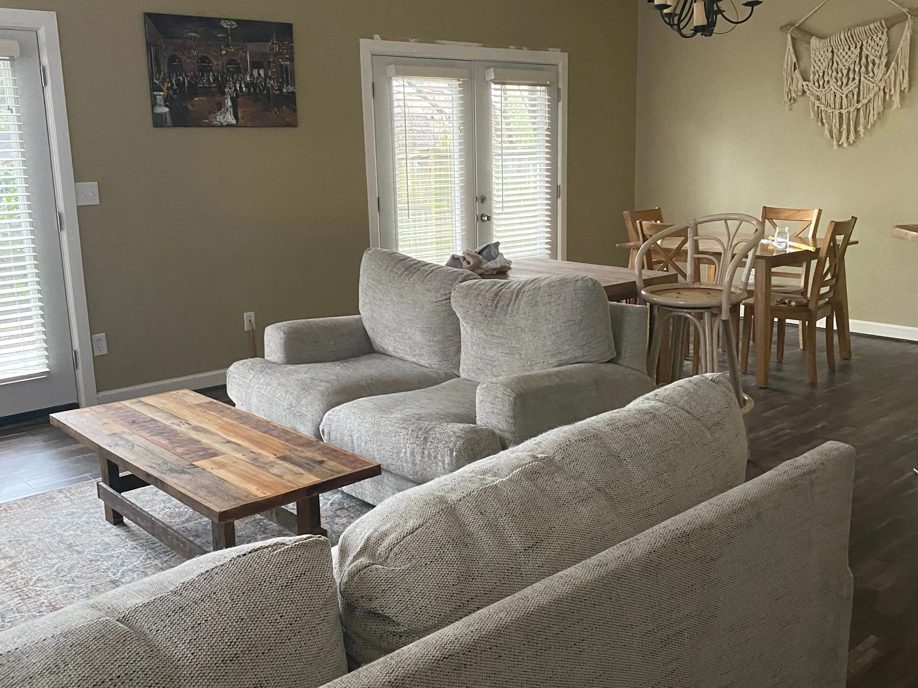 Living room with green walls, light gray couches, and vinyl-plank flooring next to French doors