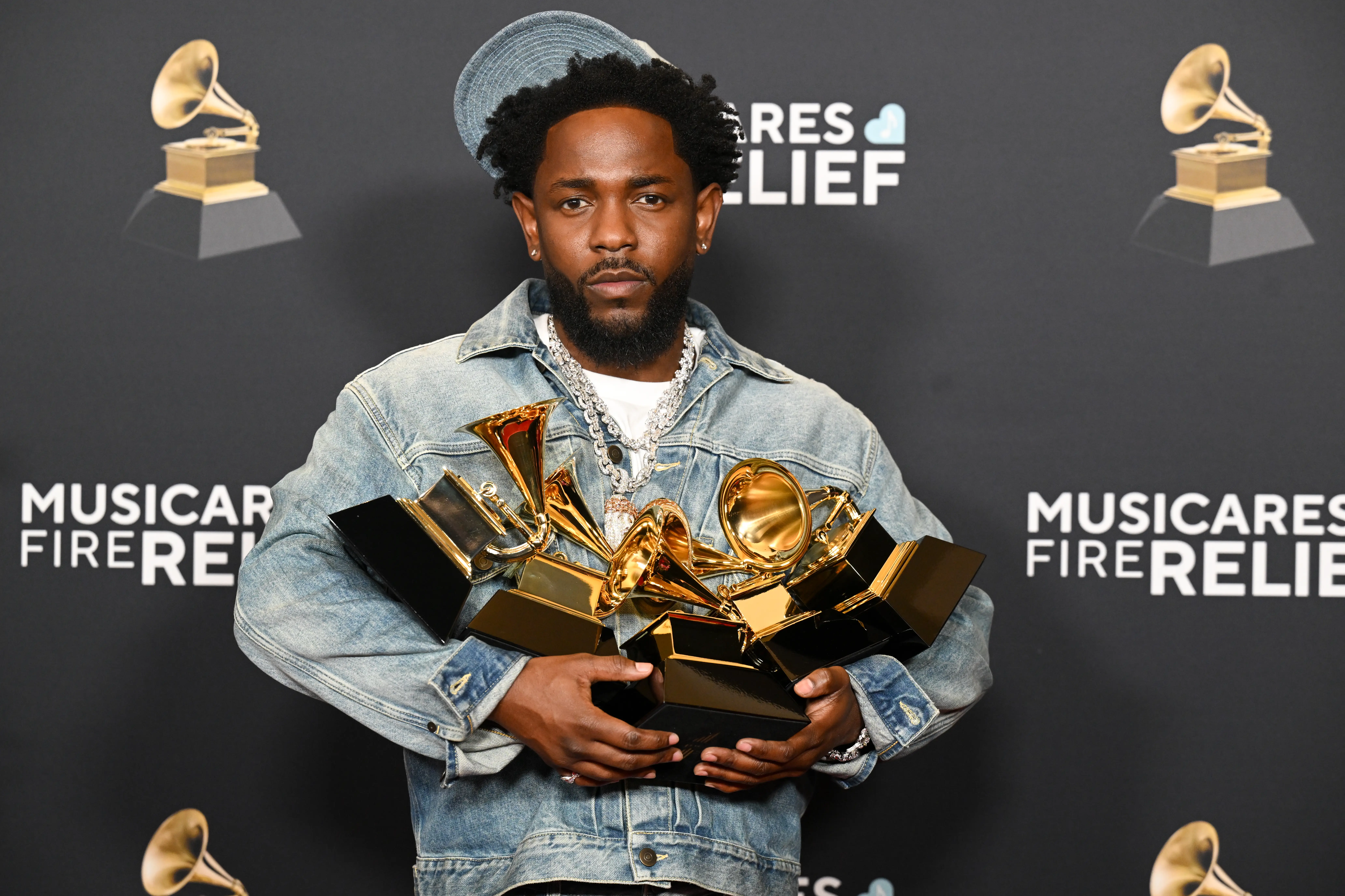 Kendrick Lamar holding his five awards at the 2025 Grammys.