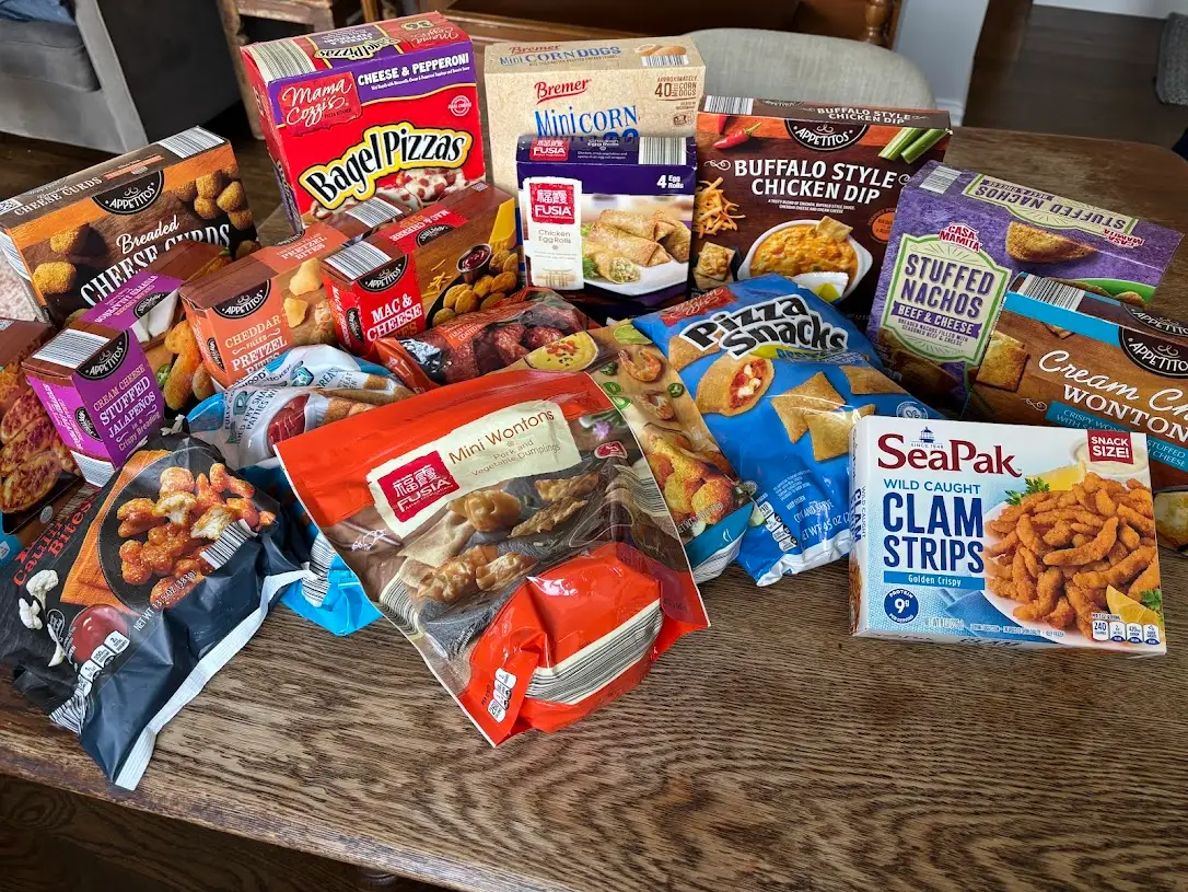A variety of frozen appetizers laid out on a wooden table.