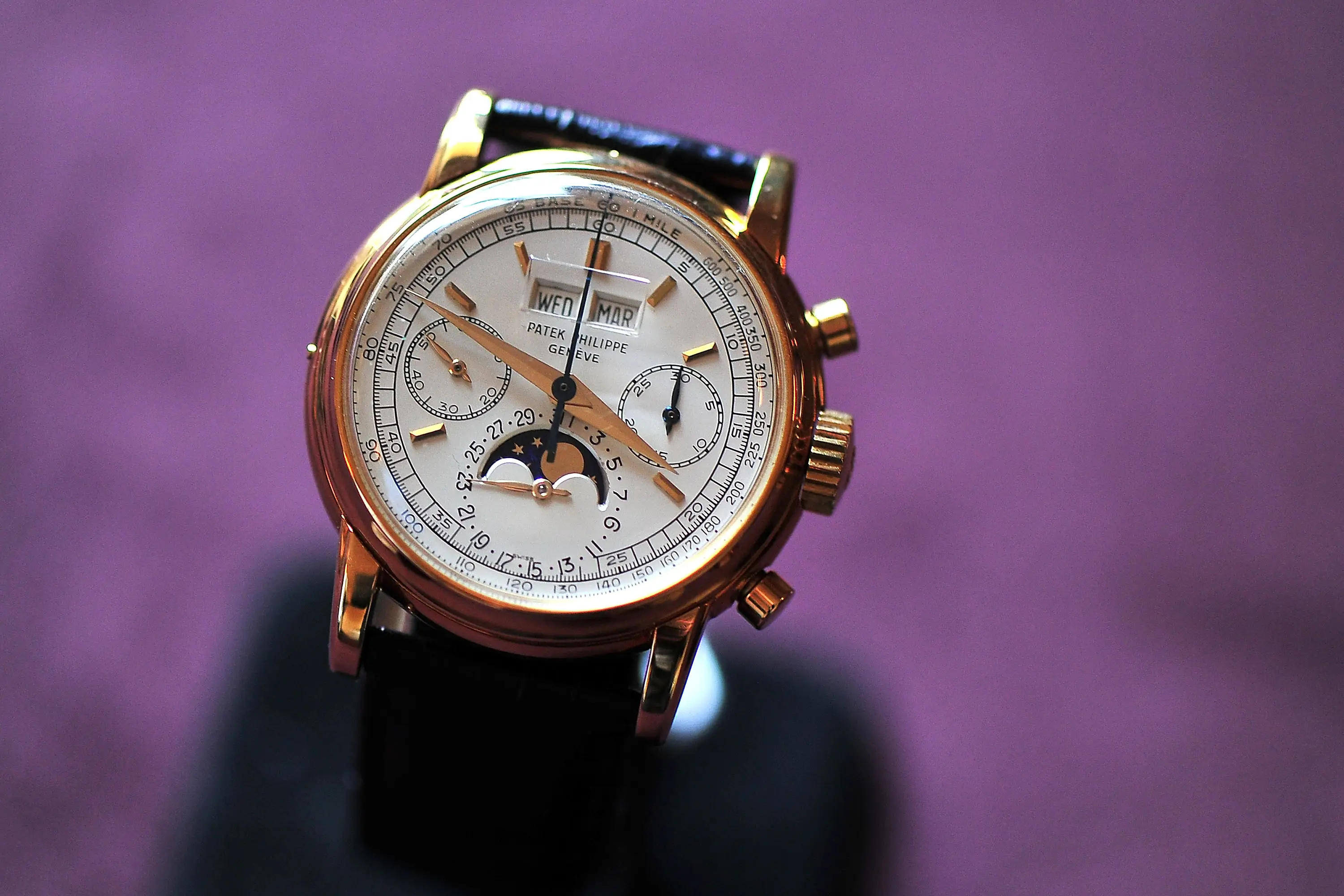 A rare yellow gold Patek Philippe  2499 watch on a purple background