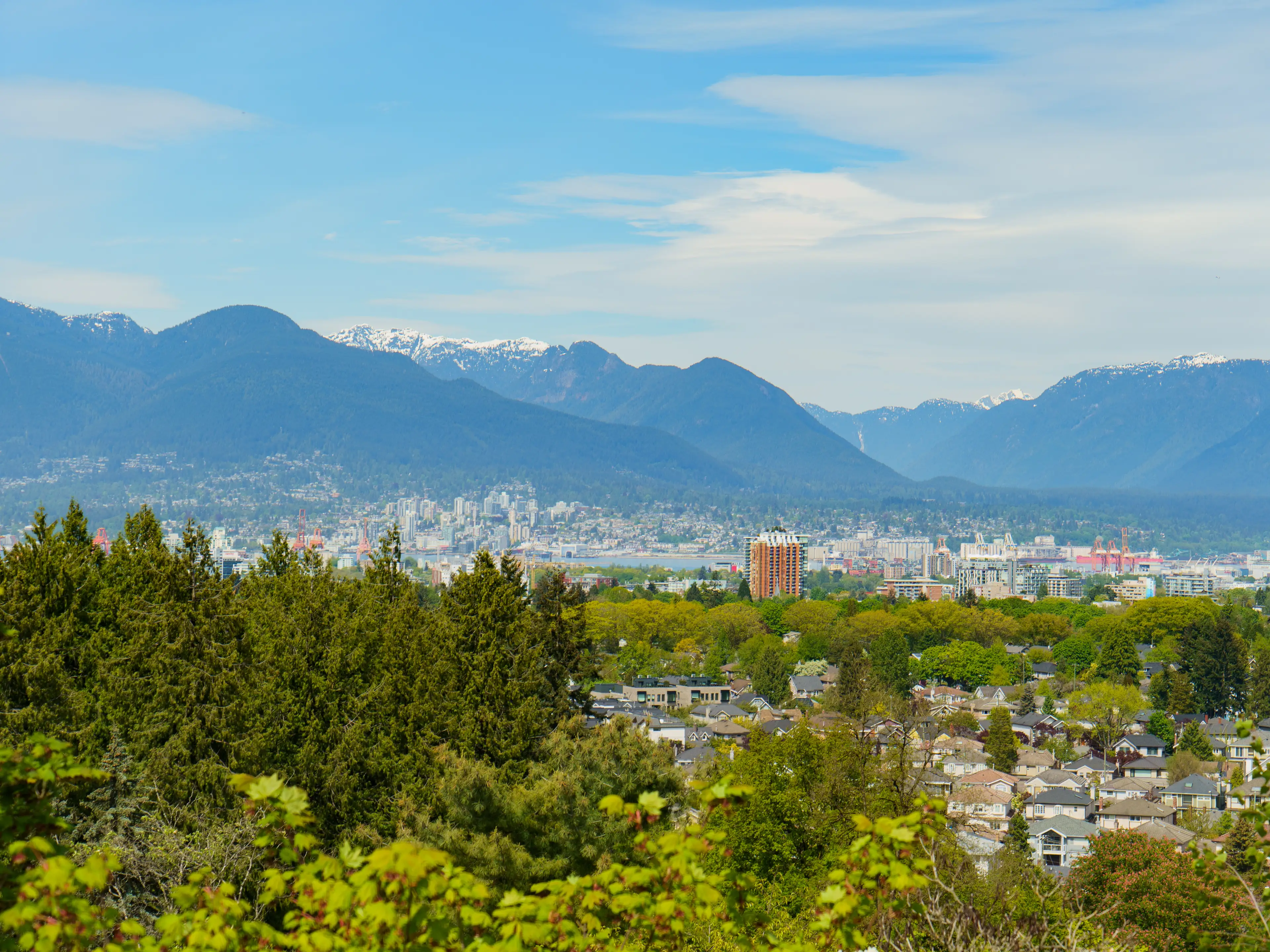 A Vancouver landscape with forests and buildings in front of mountains