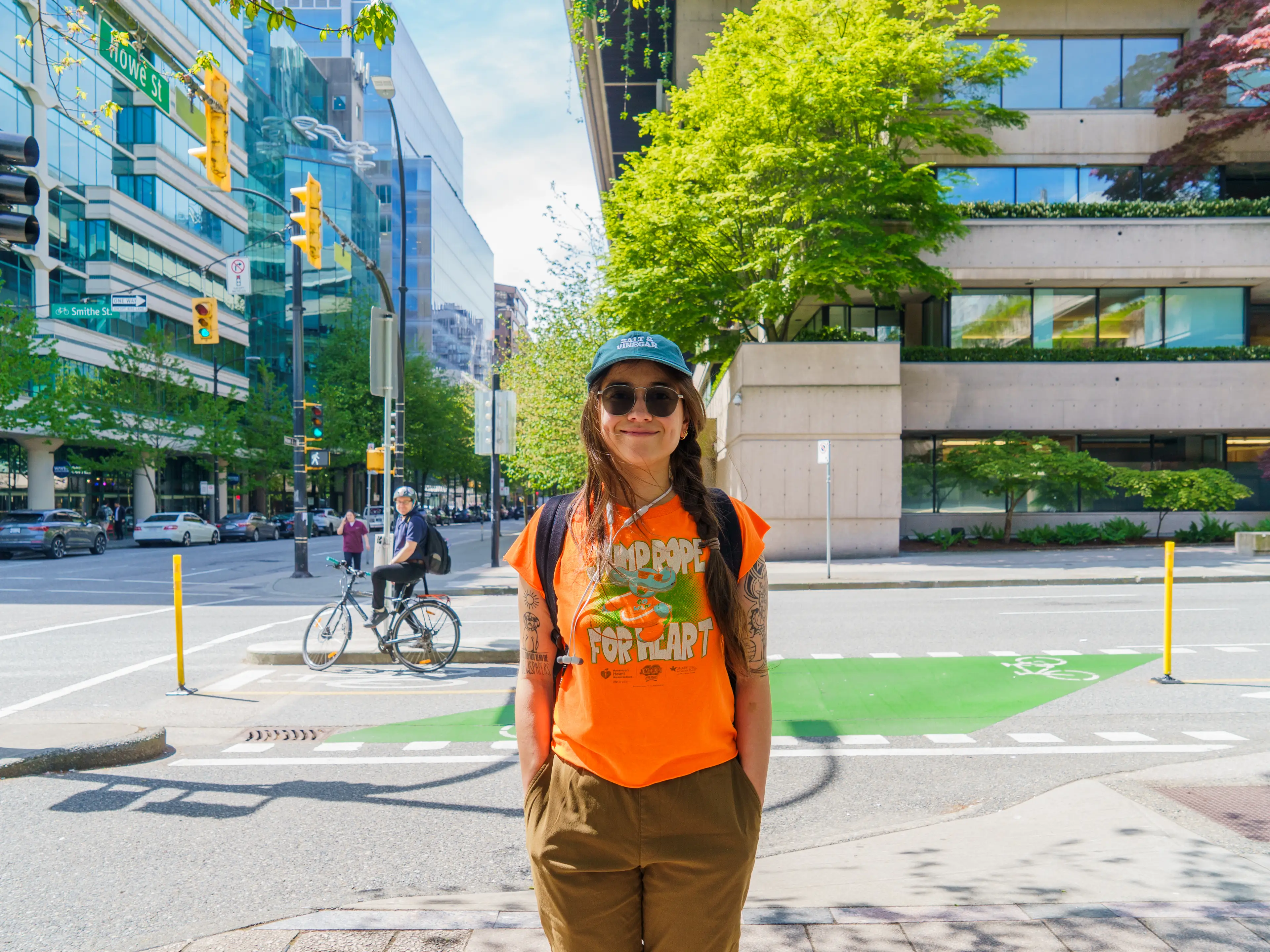The author stands smiling in downtown Vancouver with buildings, streets, and trees in the background