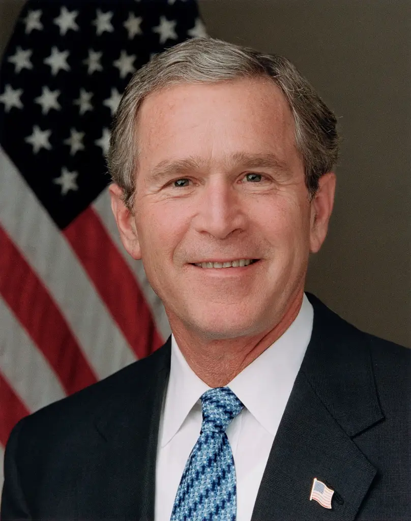 President George W. Bush poses for his official portrait in the Roosevelt Room in a blue tie.