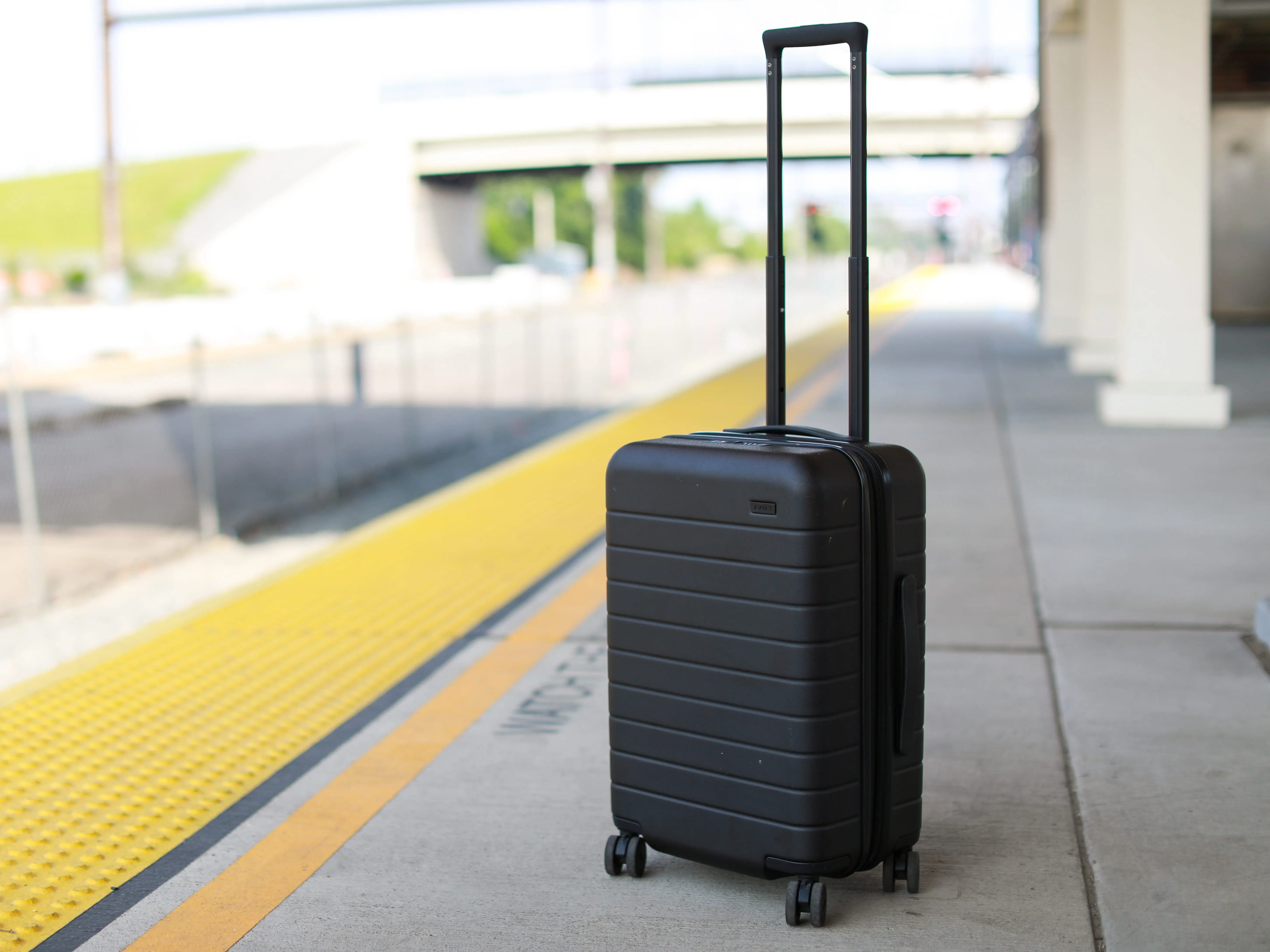 A black suitcase with wheels and a tall handle on a train platform.