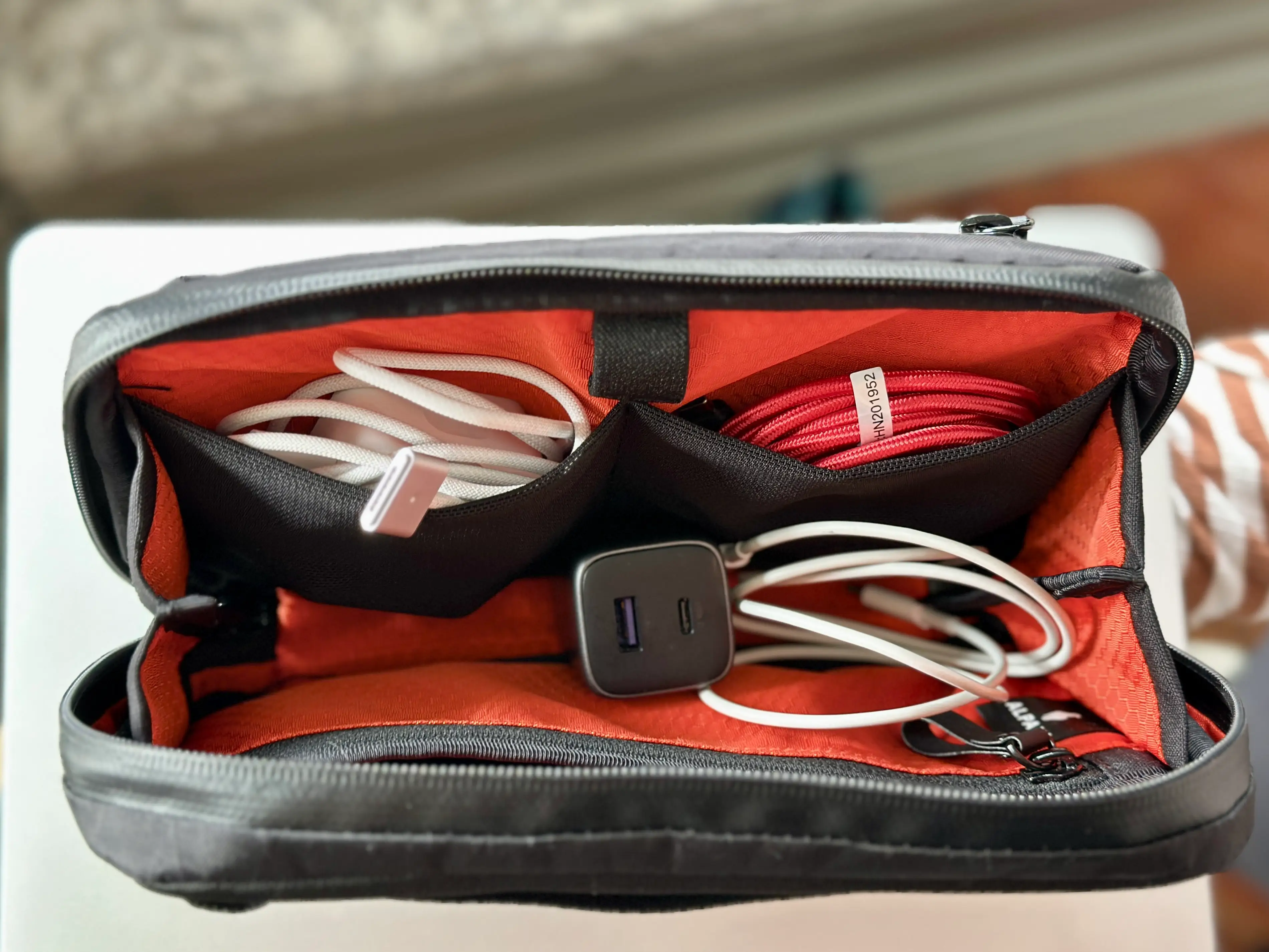 An unzipped bag with charging cables inside.