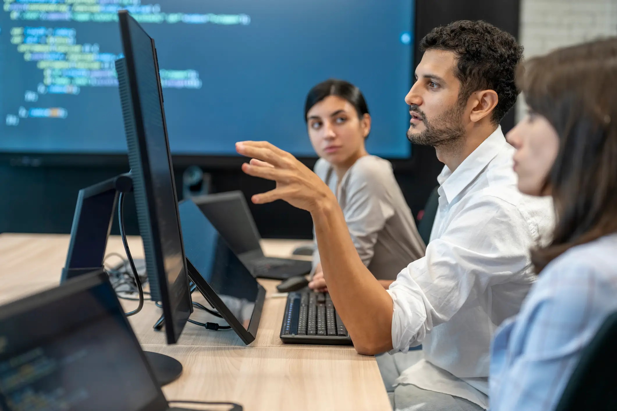 Software developers checking programming code on computer screen.